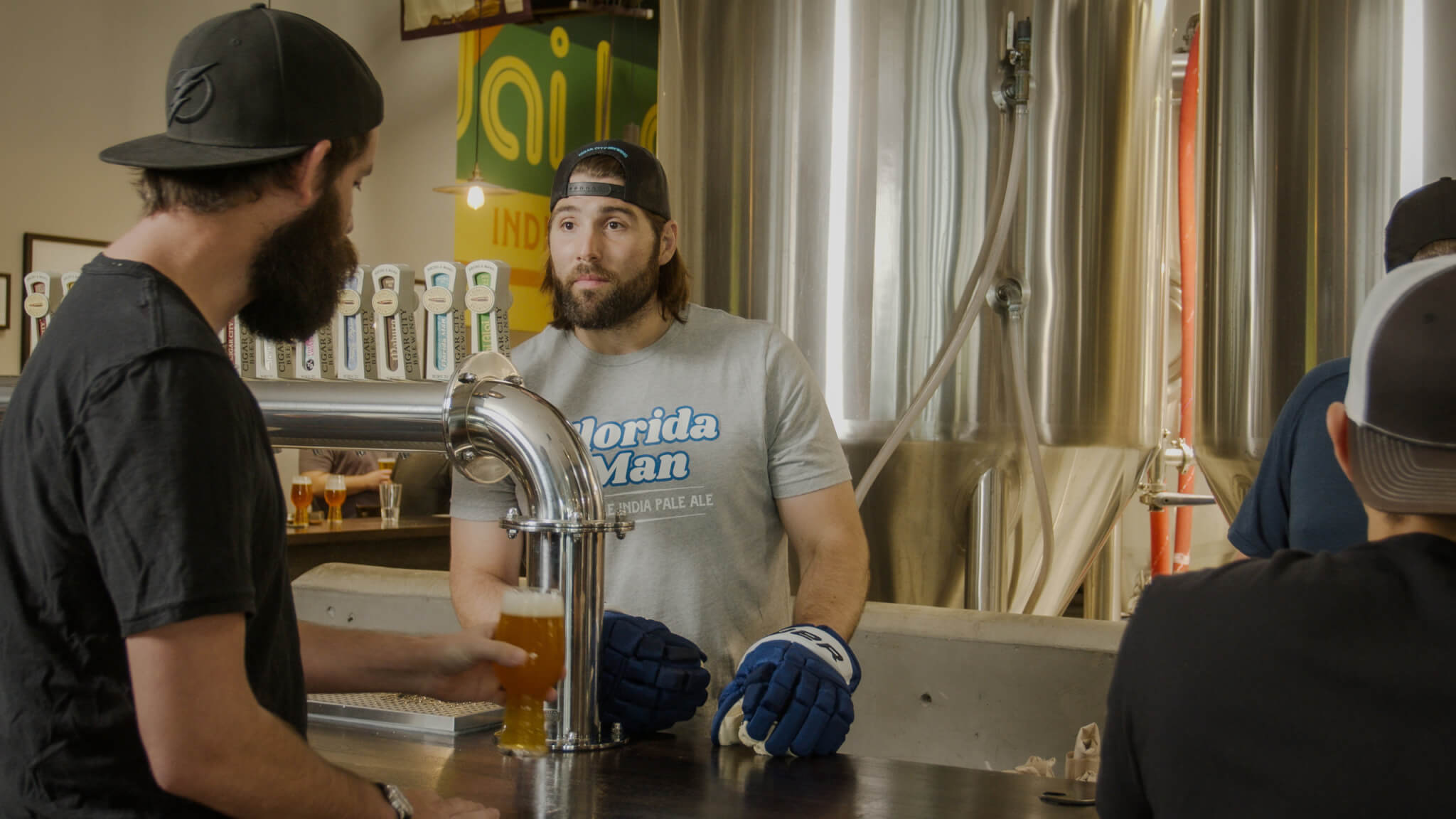 Tampa Bay Lightning's Pat Maroon attempts to open a can of Florida Man Double IPA while working on the canning line at Cigar City Brewing's Spruce Street brewery while a CCB staff member watches.